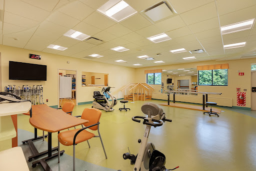 A spacious rehabilitation exercise room equipped with various gym apparatus for physical therapy.