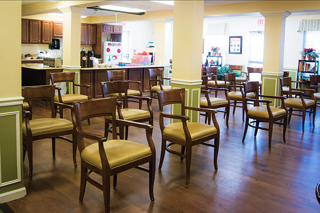 A community dining area with several chairs arranged on a wooden floor.
