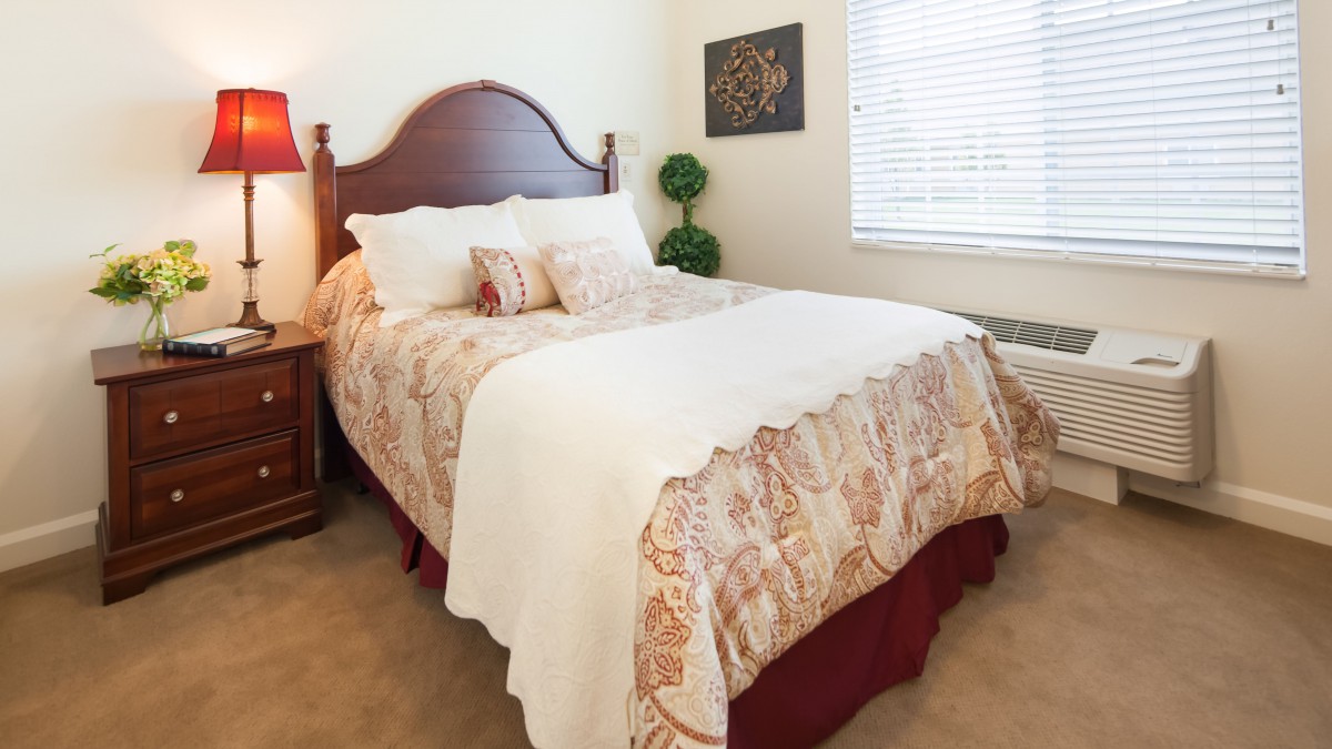A cozy bedroom with a neatly made bed, featuring patterned bedding and decorative pillows.
