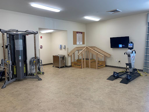A spacious rehabilitation gym featuring various exercise equipment and a stair training area.