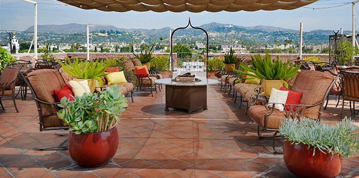 A stylish rooftop patio with comfortable seating, lush plants, and a scenic view of the surrounding hills.
