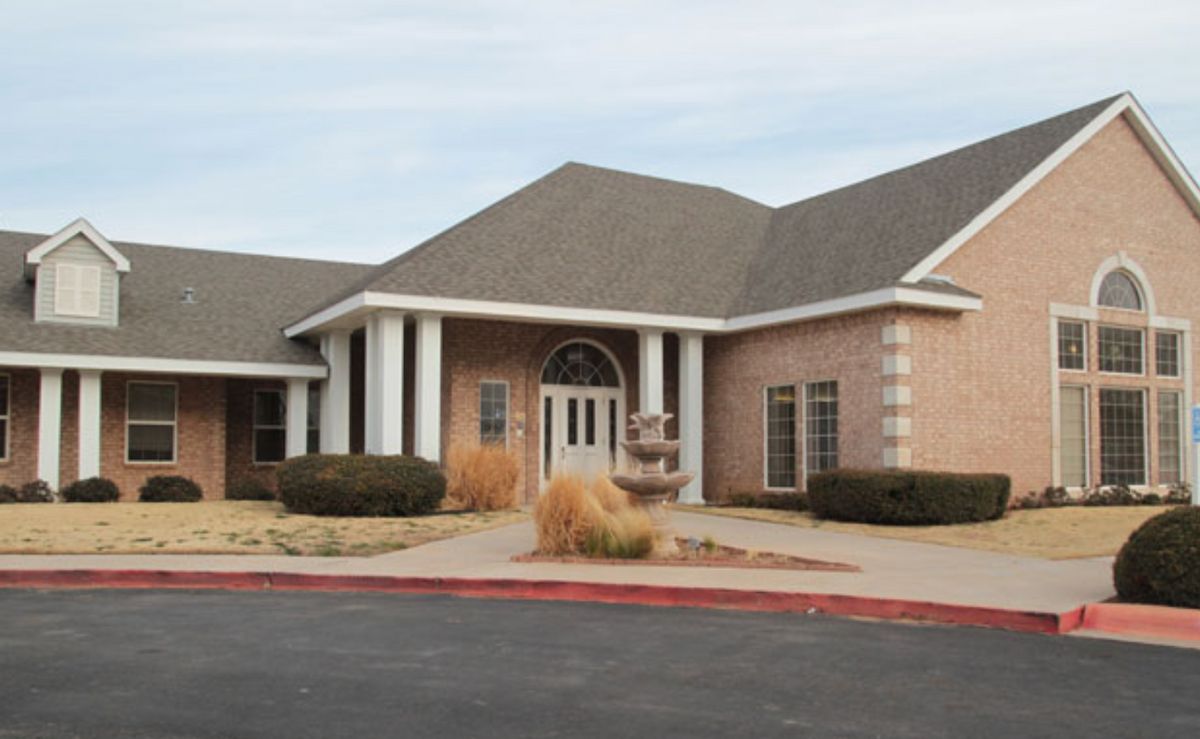 A suburban brick building with a prominent entrance and landscaping.