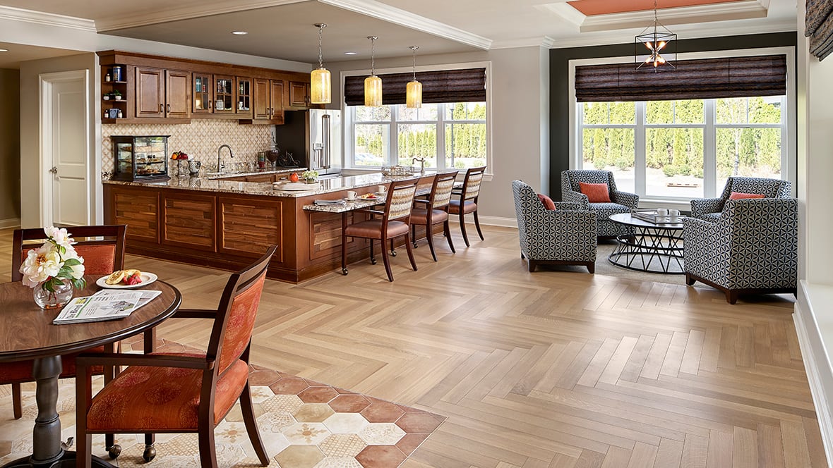 A modern open-concept space featuring a kitchen with wooden cabinets and an island, a dining area, and a cozy seating corner.