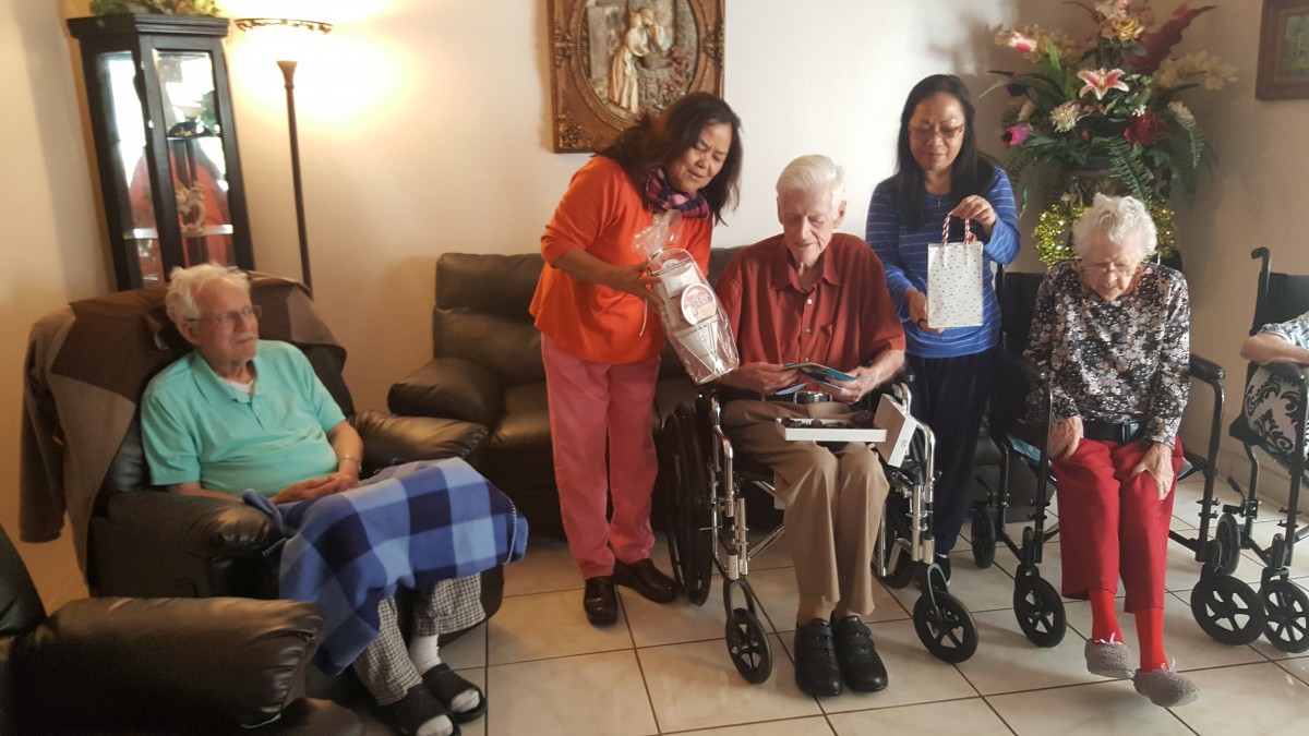 A group of people, including caregivers and elderly individuals, interacting in a home setting.