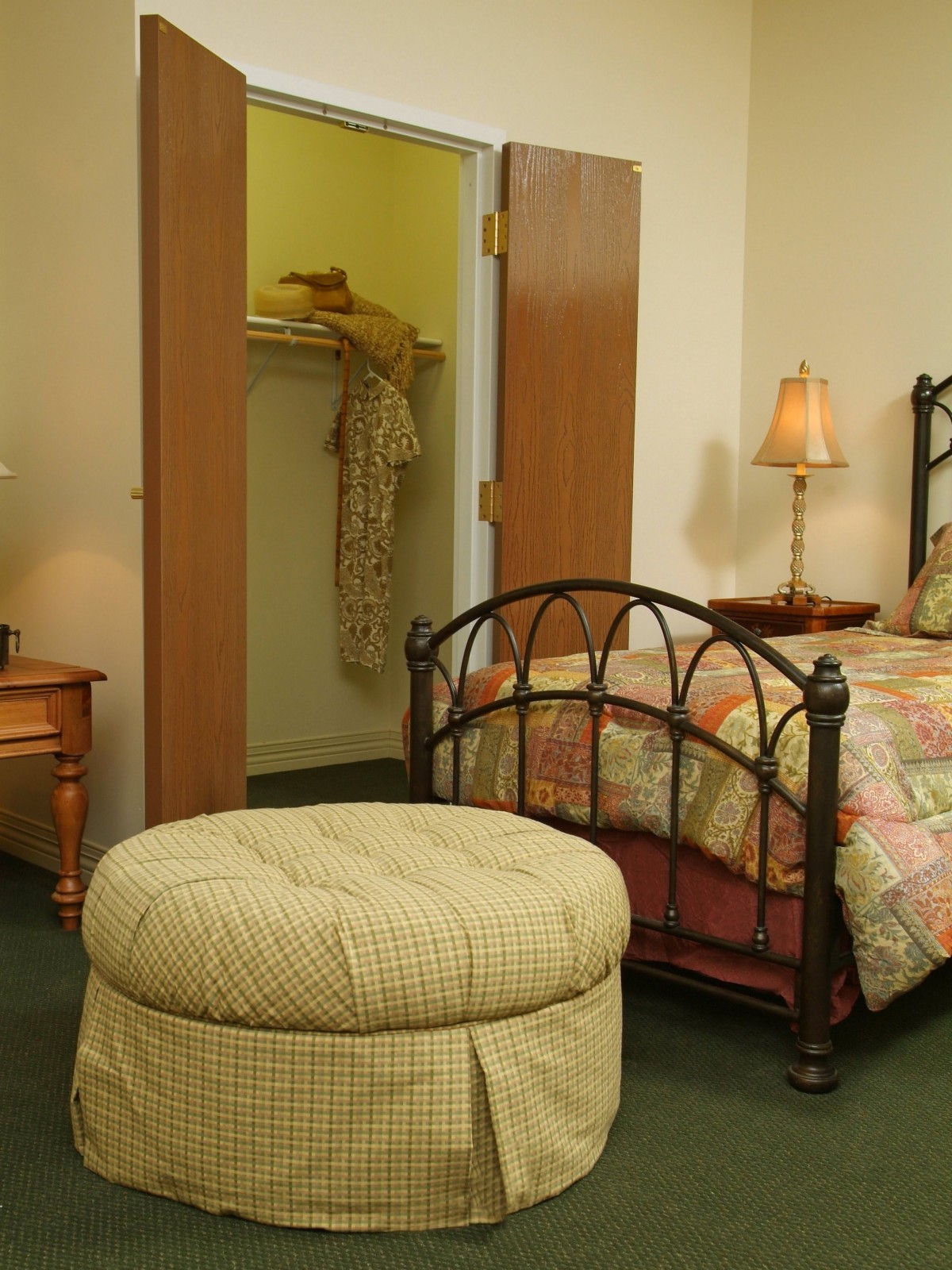 A cozy bedroom with a bed, lamp, and open closet.