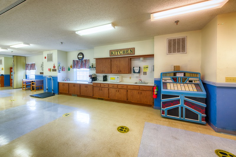 A bright and spacious daycare kitchen area with wooden cabinets and a colorful safety gate.