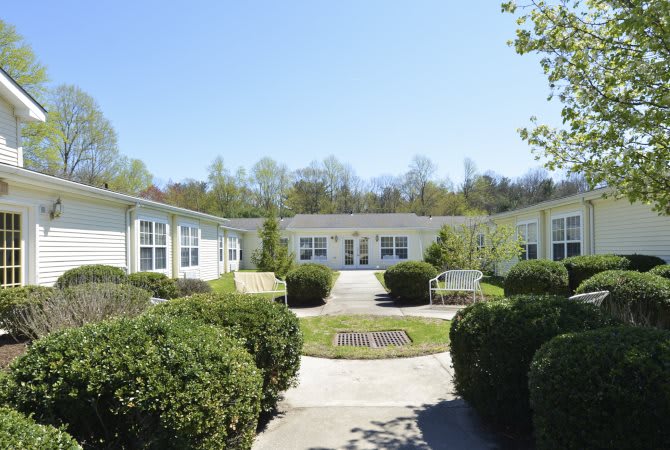 A sunny courtyard surrounded by residential buildings and landscaped shrubs.