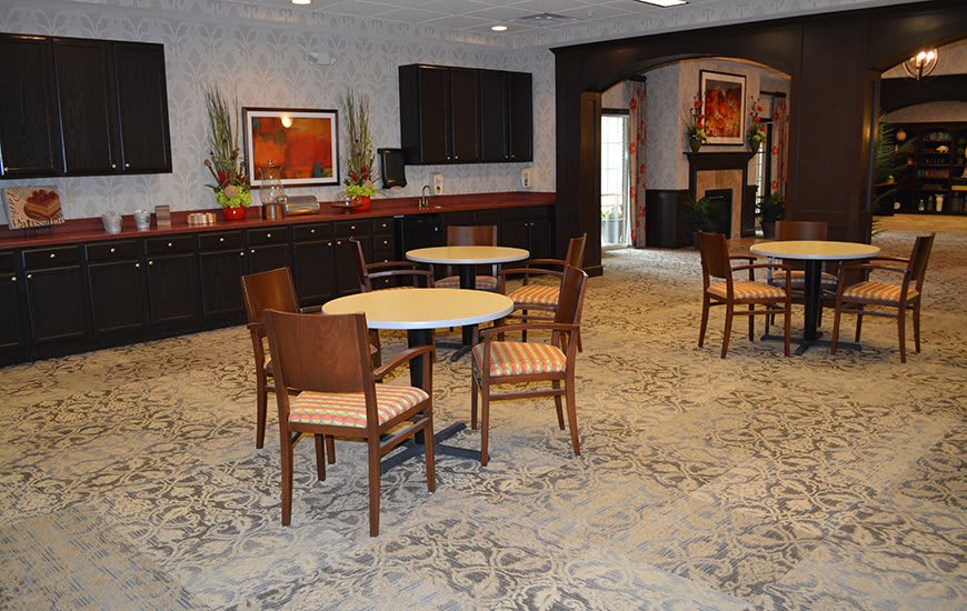A cozy seating area with round tables and chairs, featuring artwork on the walls.