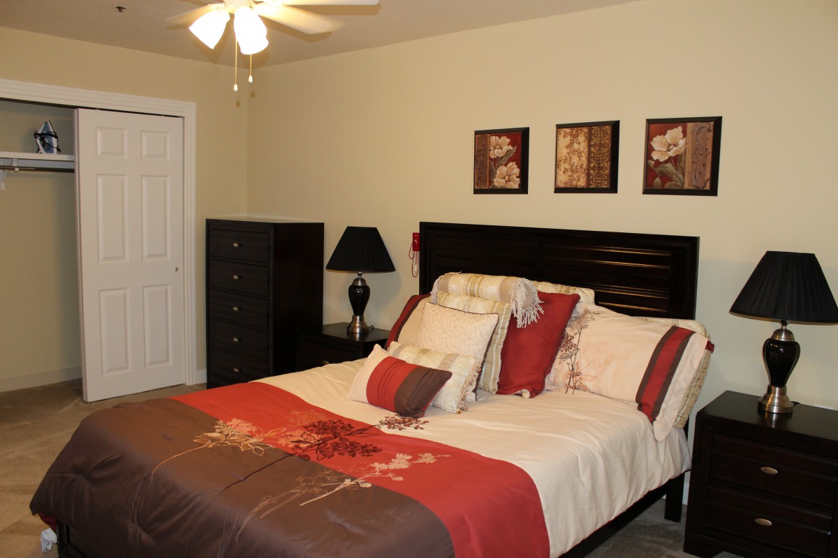 A well-decorated bedroom with a neatly made bed, vibrant pillows, and tasteful artwork on the walls.