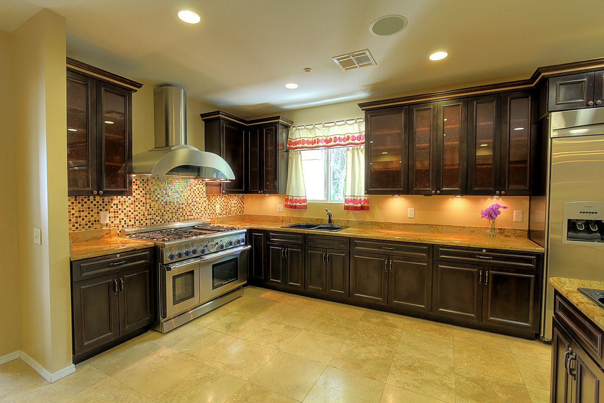 A modern kitchen with dark wood cabinets, stainless steel appliances, and a tile backsplash.