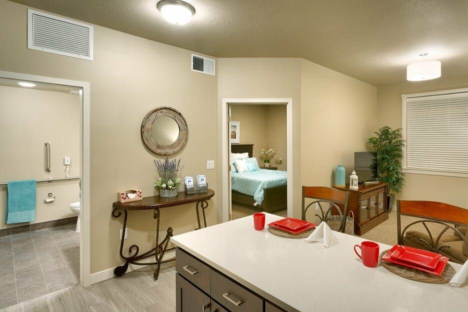 A modern interior featuring a kitchen with a dining area and a view into the bedroom, showcasing tasteful home decor.