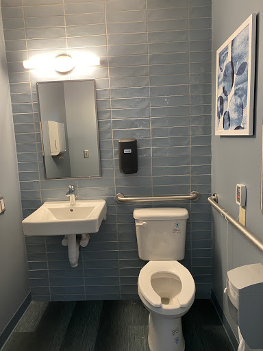 A clean and modern bathroom featuring a toilet, sink, and mirror with blue tiled walls.