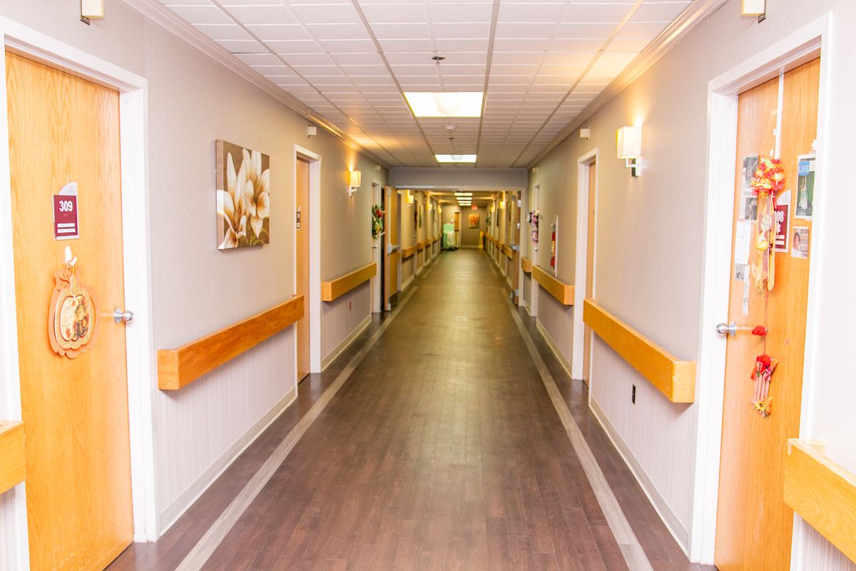 A well-lit hospital corridor with handrails and artwork on the walls.