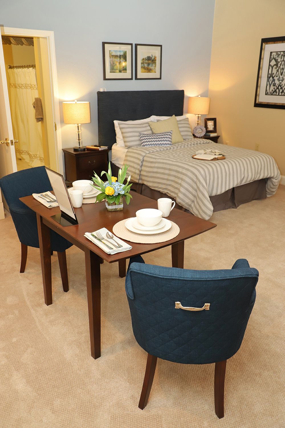 A cozy bedroom with a small dining area featuring a neatly set table and comfortable chairs.