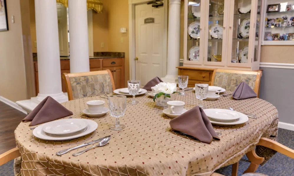 An elegantly set dining room table with neatly arranged place settings and napkins.