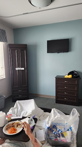 A view of a simple bedroom featuring a wardrobe, dresser, and wall-mounted television.