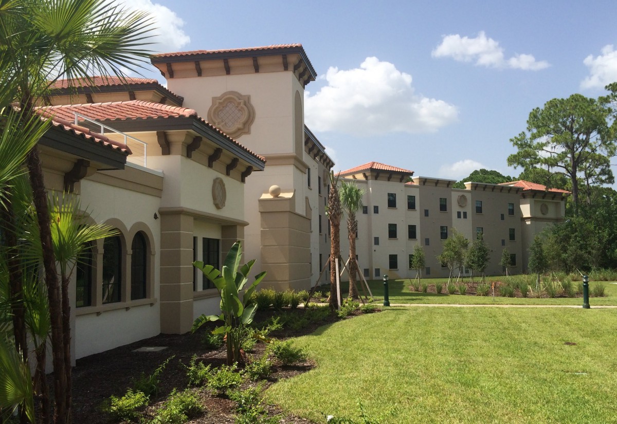 A view of a campus building with a well-maintained lawn and clear blue sky.