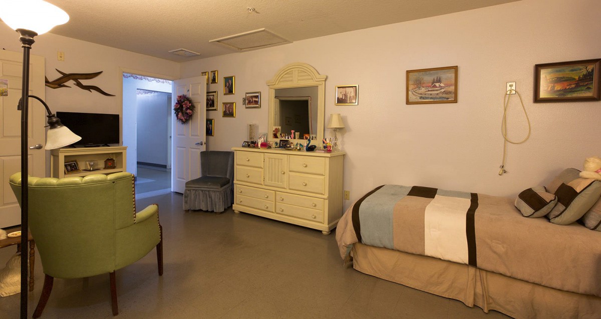 A cozy bedroom with a dresser and a mirror, adorned with various decorations and a neatly made bed.