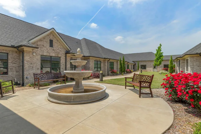 A peaceful courtyard with a central fountain, surrounded by benches and landscaped gardens in a residential setting.