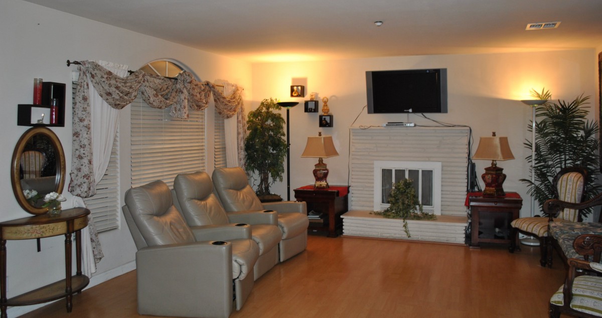 A cozy living room featuring recliner seating, a television mounted above the fireplace, and tasteful decor.