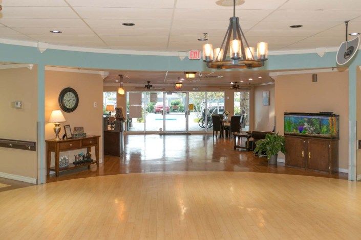 Spacious lobby with a chandelier and hardwood floors leading to an entrance.
