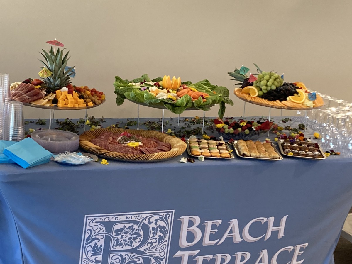 A beautifully arranged buffet table with a variety of appetizers and platters, covered by a cloth labeled 'Beach Terrace.'