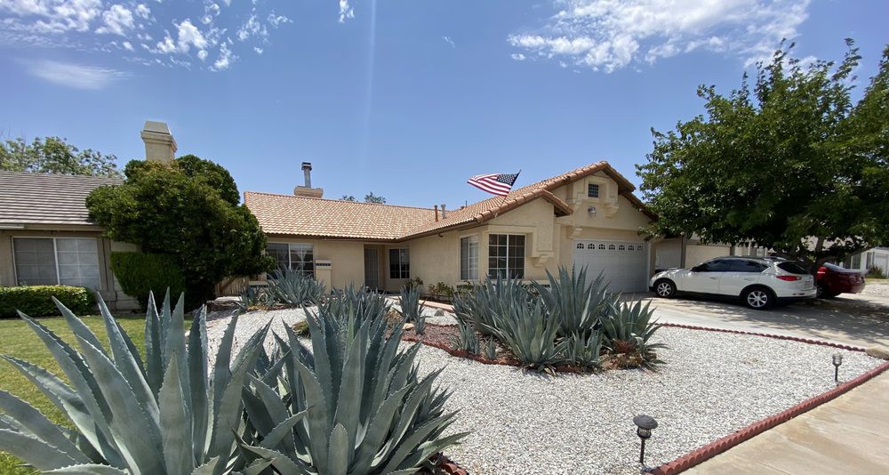 A suburban house with desert landscaping featuring succulents and an American flag.