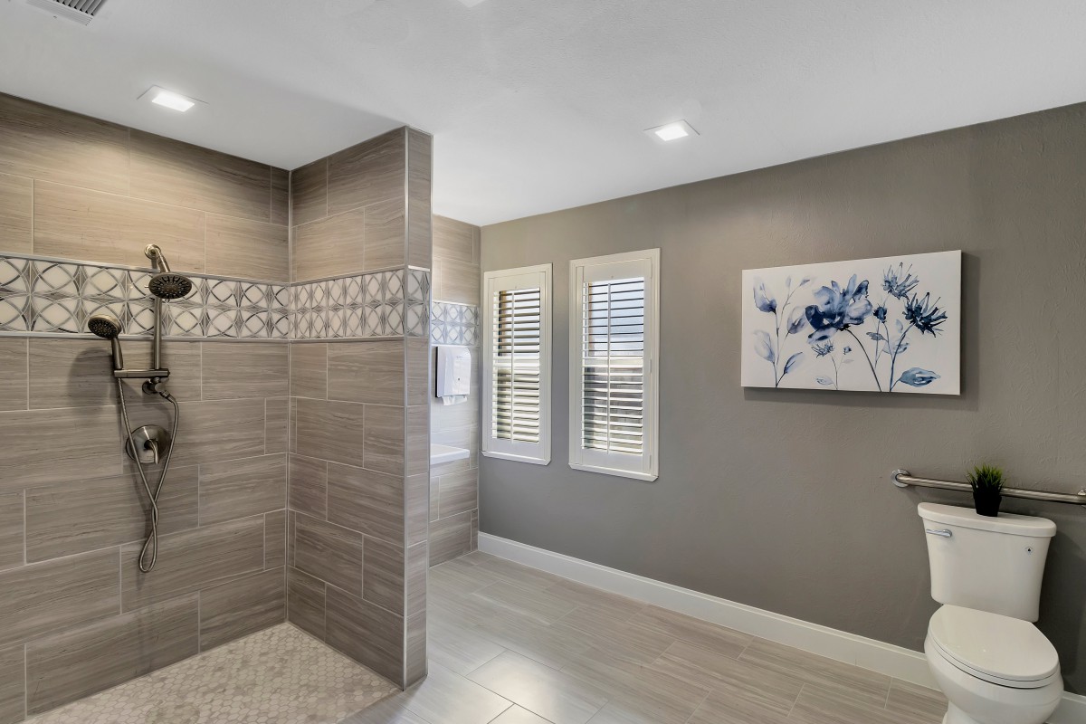 A modern bathroom featuring a tiled shower and framed artwork on the wall.