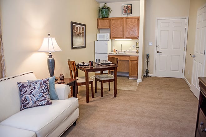 A cozy apartment with an open-concept living and dining area, featuring a sofa, a small dining table with chairs, and a compact kitchen.