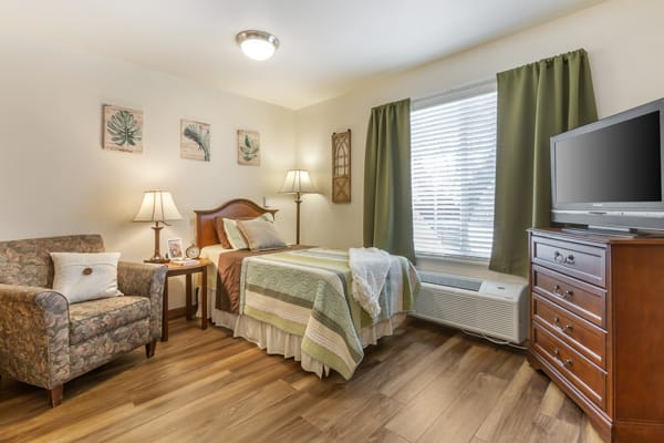A cozy bedroom with a single bed, wooden floor, and elegant decor.
