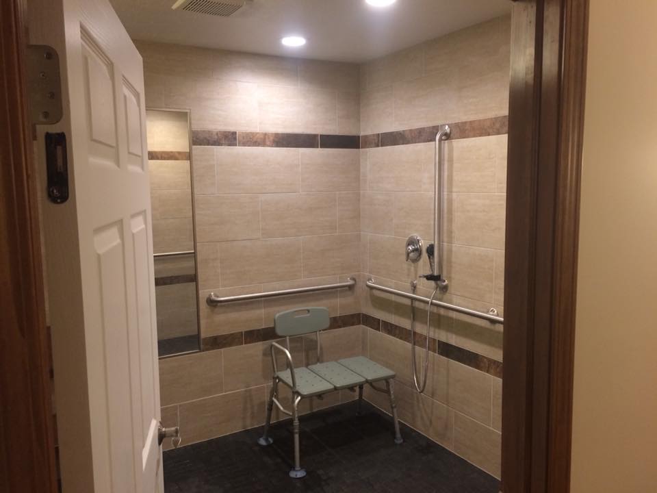 An accessible bathroom with a shower seat and grab bars.