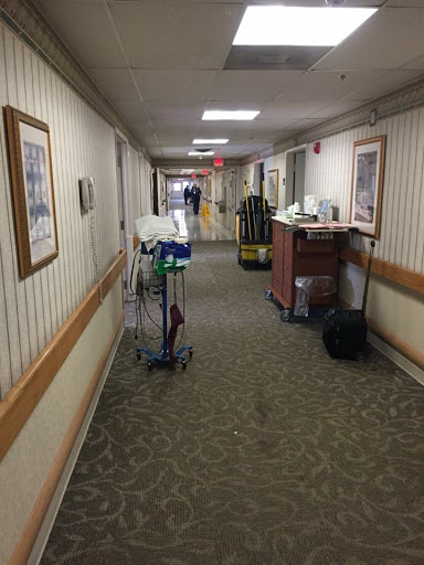 A hallway in a healthcare facility featuring medical equipment and a warm interior design.