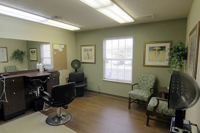 A cozy barber shop interior featuring chairs, a mirror, and artwork on the walls.