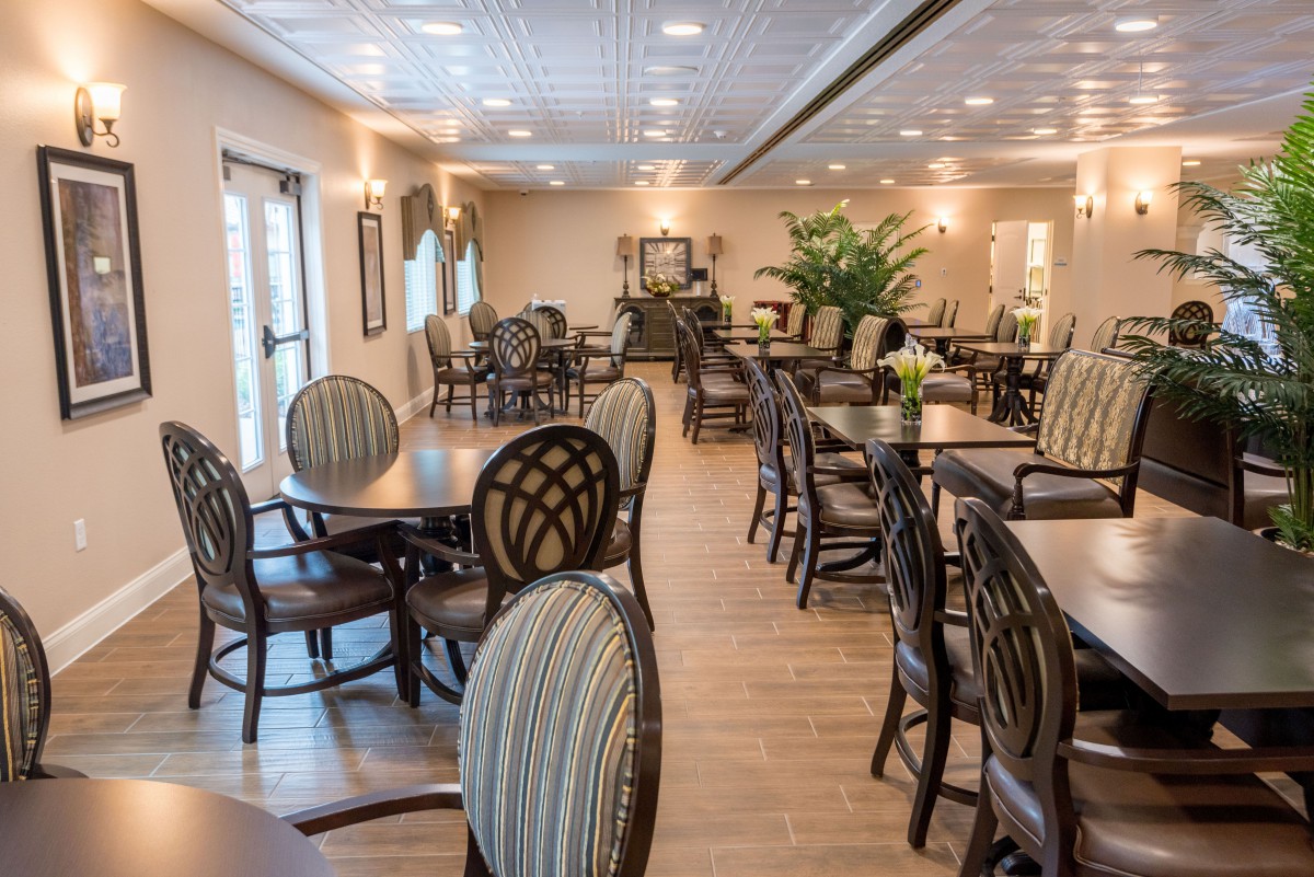 Elegant dining area with arranged tables and chairs, featuring warm lighting and greenery.