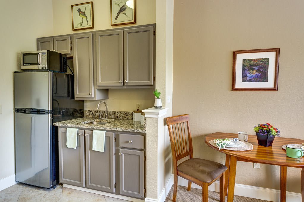 A cozy kitchen with gray cabinets and a small dining table set for two.