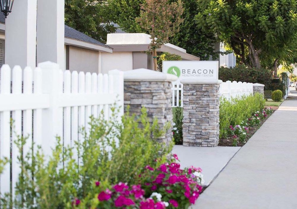 A scenic pathway lined with a white fence and vibrant flowers.