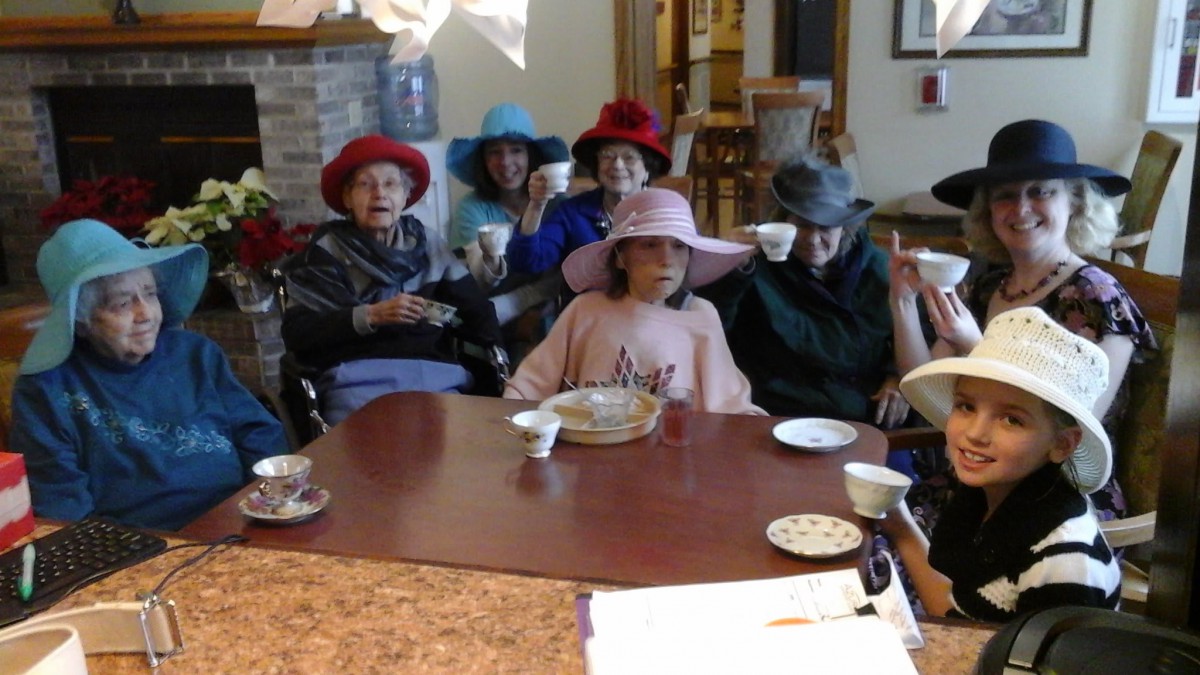 A group of elderly individuals enjoying a tea party, wearing colorful hats.