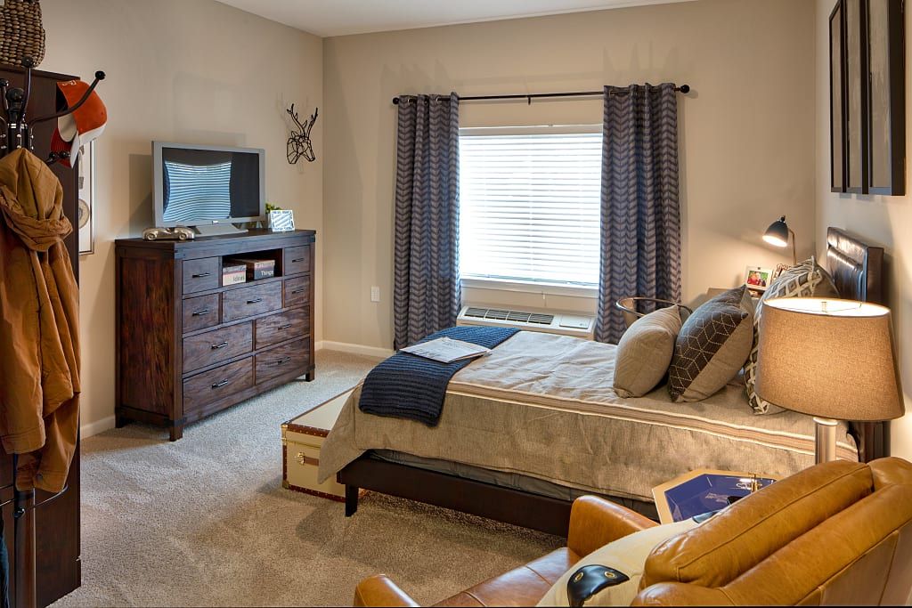 A cozy and well-furnished bedroom with a bed, dresser, and window.