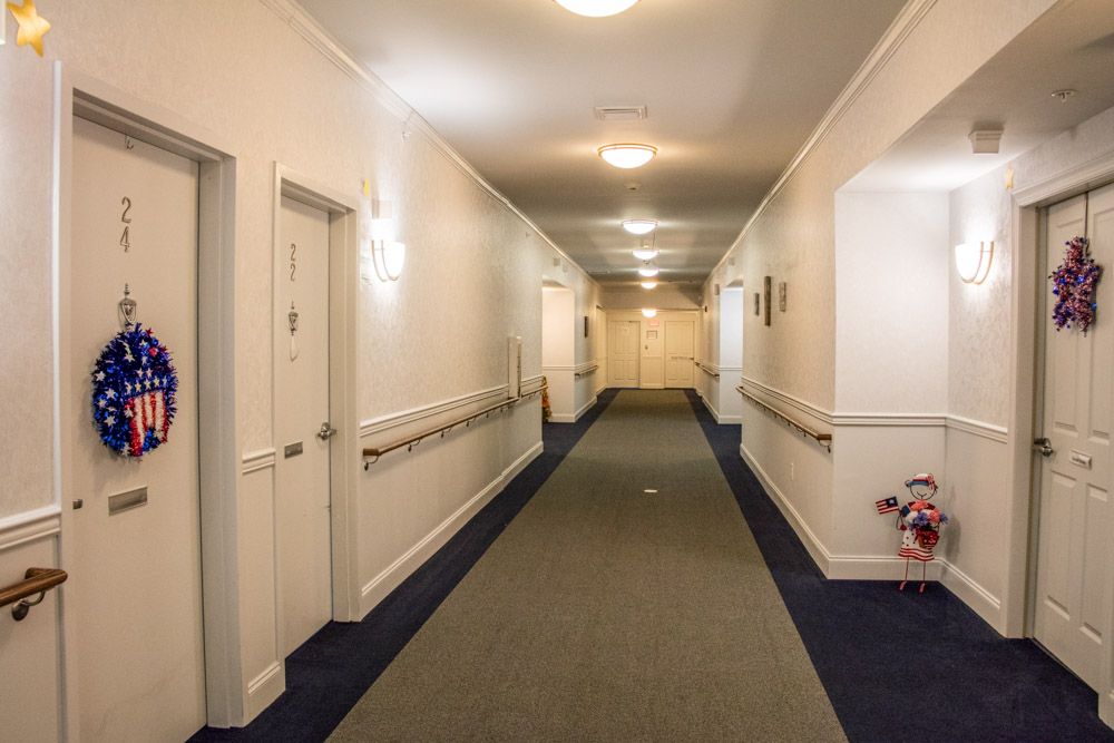 A well-lit hallway with carpeted floors and handrails on the walls.