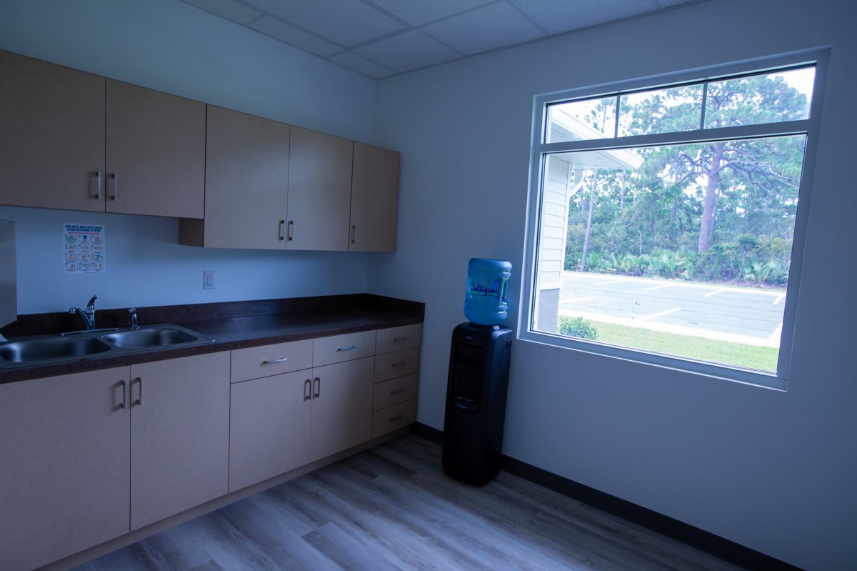Office kitchen area with cabinets, a water cooler, and a window.