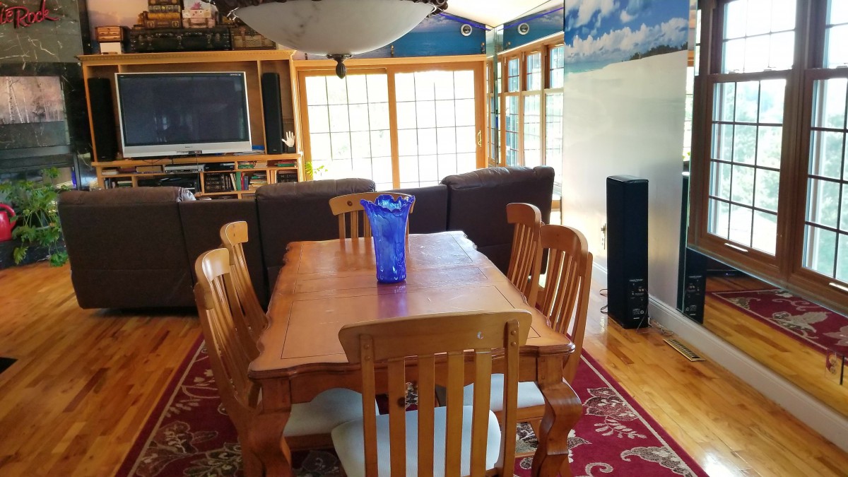 A cozy dining and living area with wooden furniture and a decorative vase on the table.