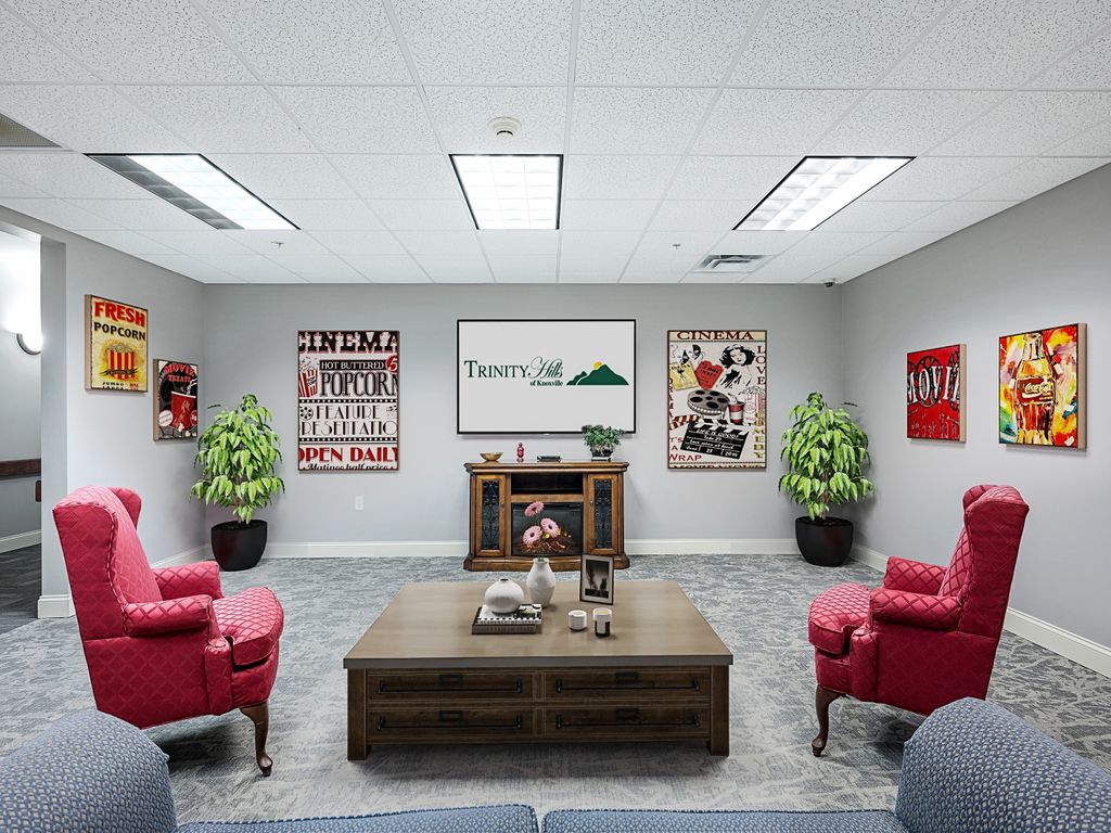 A well-decorated office space featuring red chairs, green plants, and various artworks on the walls.
