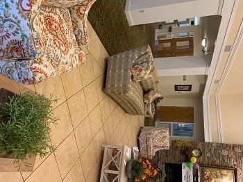 A cozy living room with sofas, armchairs, and a coffee table on tiled flooring.