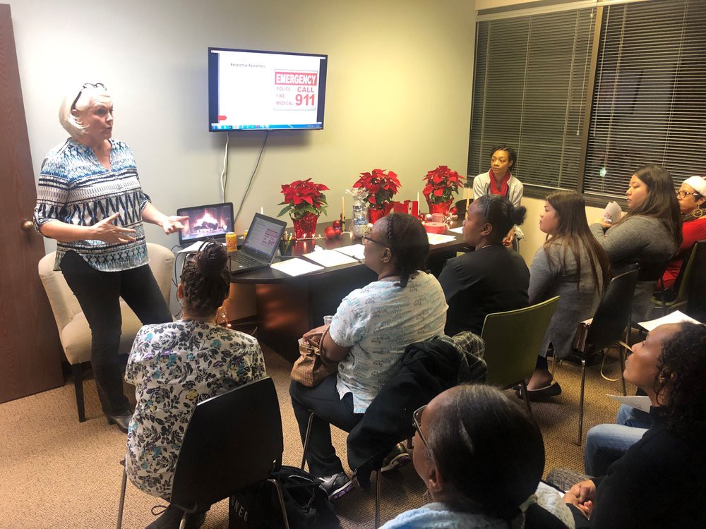 A group of people attending a meeting in an office setting, with a presentation displayed on a screen.