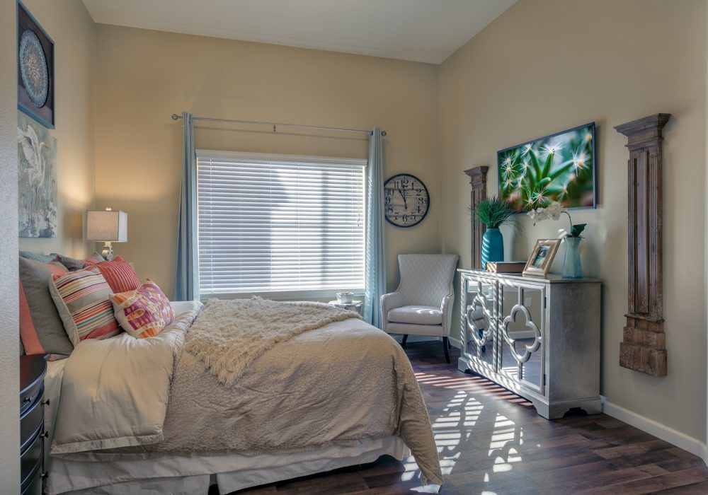 A cozy bedroom with a neatly made bed, stylish decor, and natural light streaming in through the window.