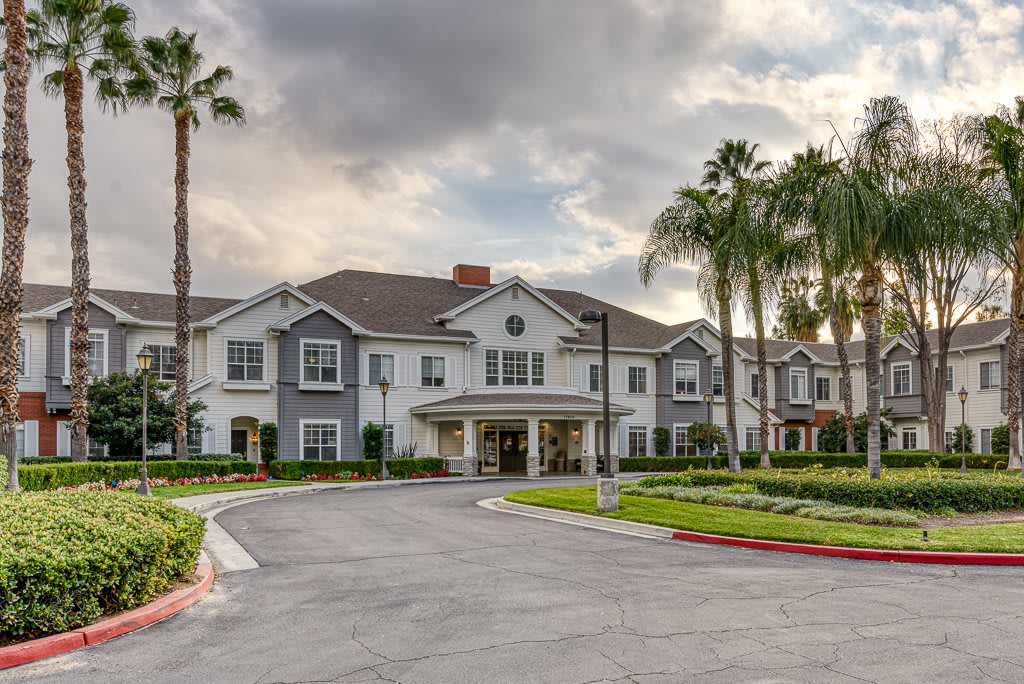 A residential building with palm trees and a driveway under a cloudy sky.