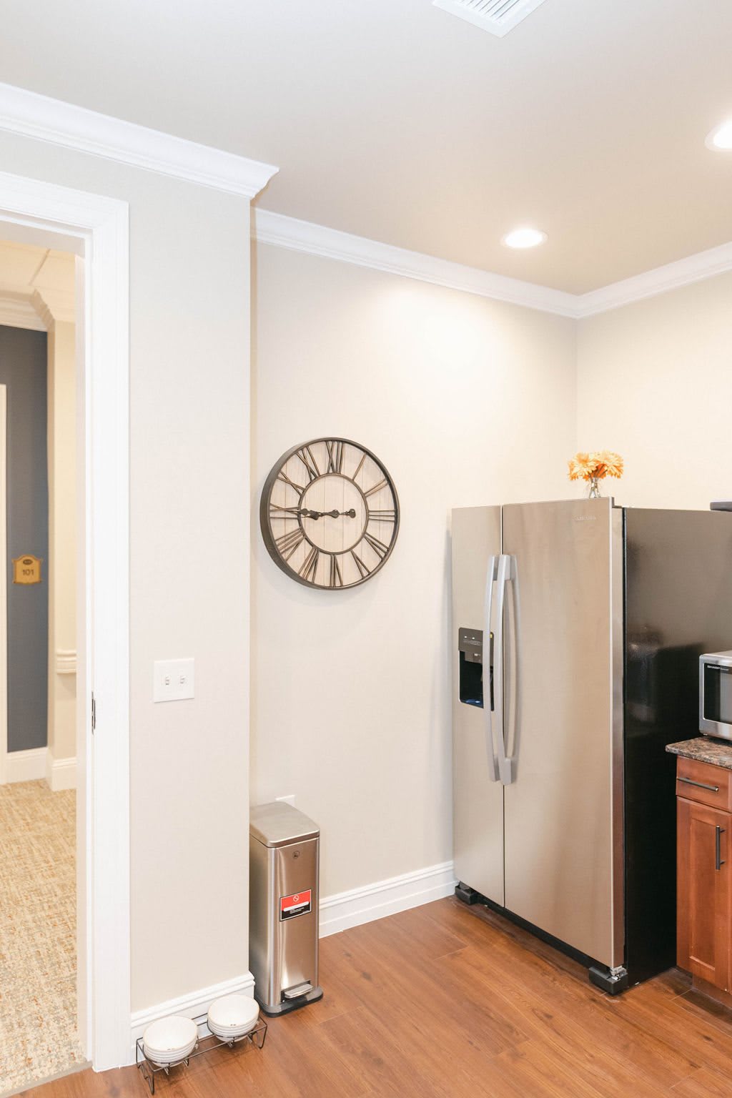 A modern kitchen featuring a stainless steel refrigerator, a wall clock, and a microwave.