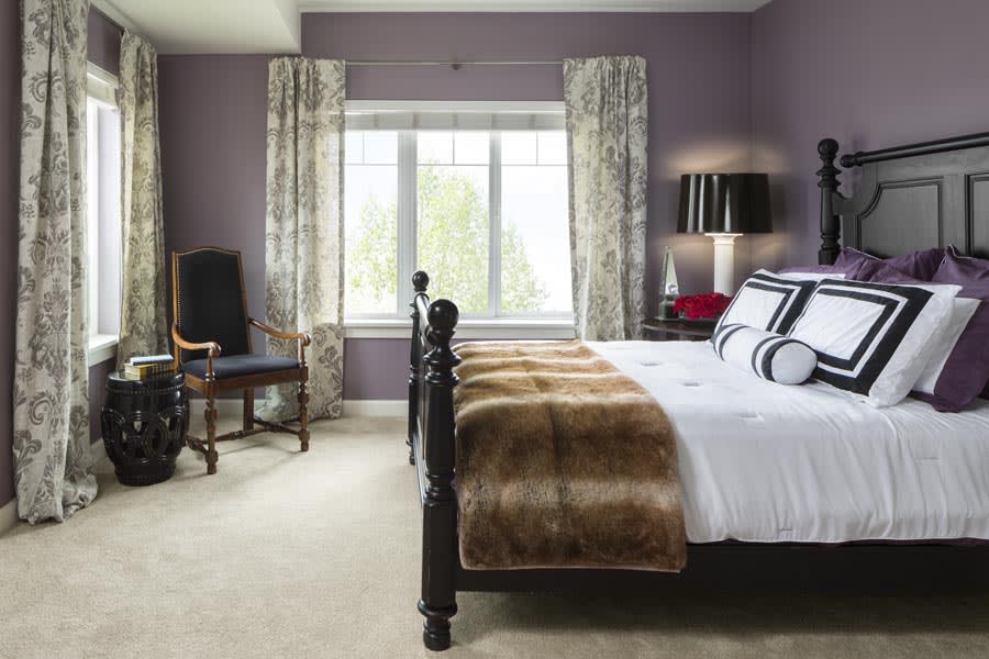 A stylish and cozy bedroom featuring a large bed, decorative pillows, and elegant curtains framing a window.