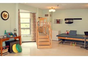 A therapy room equipped with exercise stairs, mats, and other rehabilitation tools.