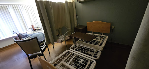 A hospital room featuring multiple beds, curtains for privacy, and basic furniture.